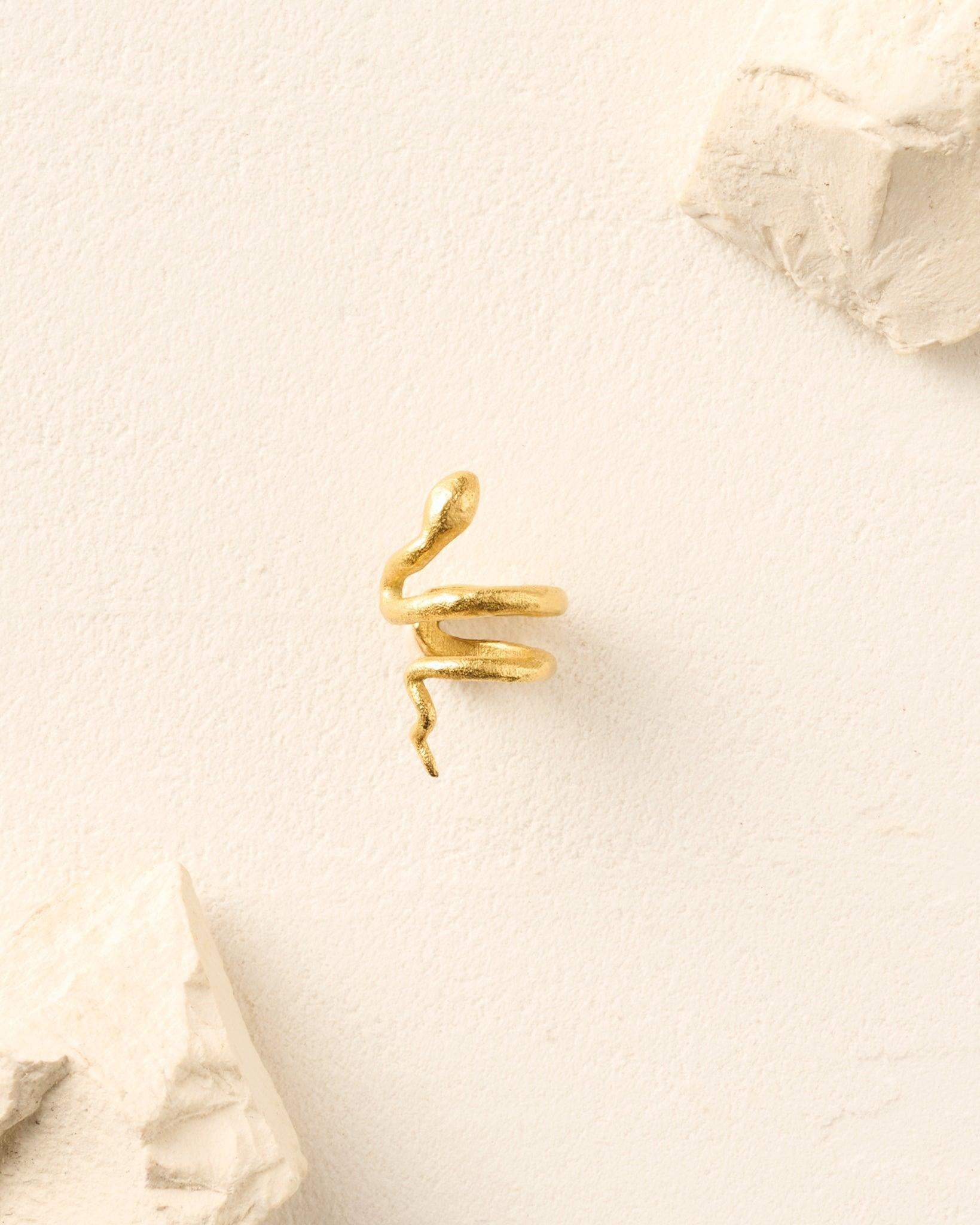 Talaia gold snake ear cuff, textured and coiled, on a light background with white stone accents.