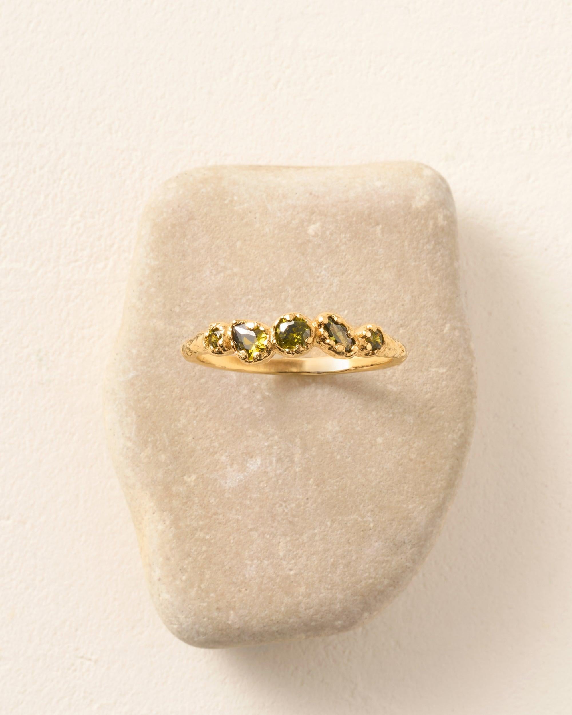 Koré green slim cluster ring with five dark green stones irregularly set in gold.