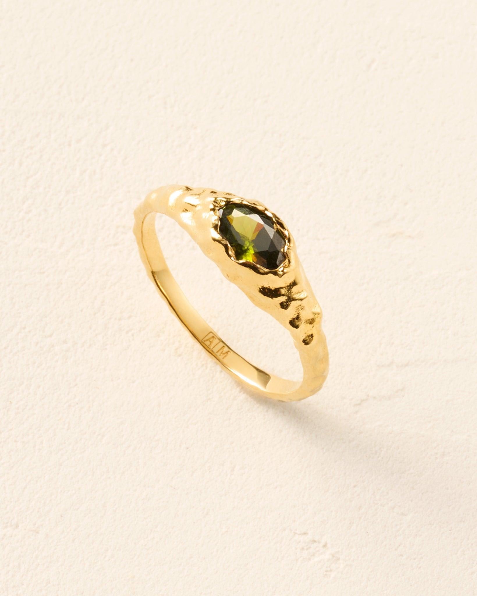 Anello Maria Mini verde: anello a cupola sottile, dorato e martellato, con una pietra ovale verde scuro sfaccettata.