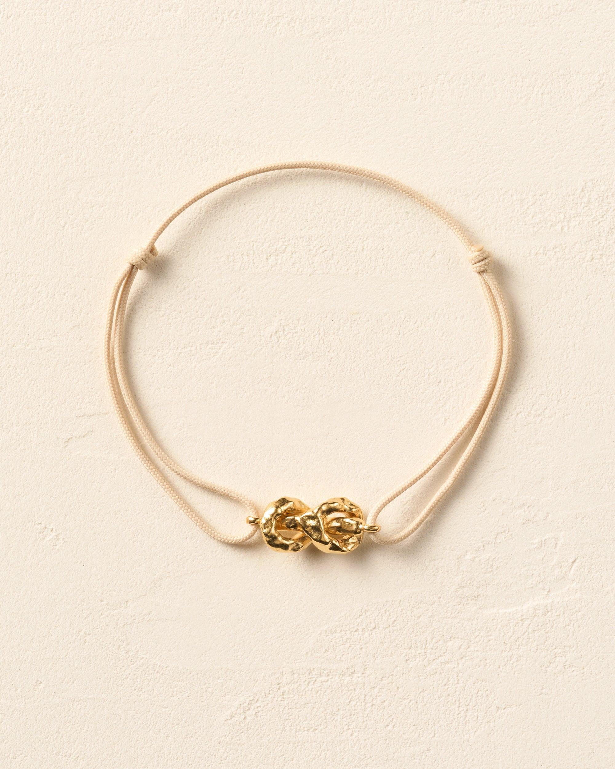 Nodéa Cord Bracelet: Gold hammered reef knot on adjustable beige waxed cotton cord.