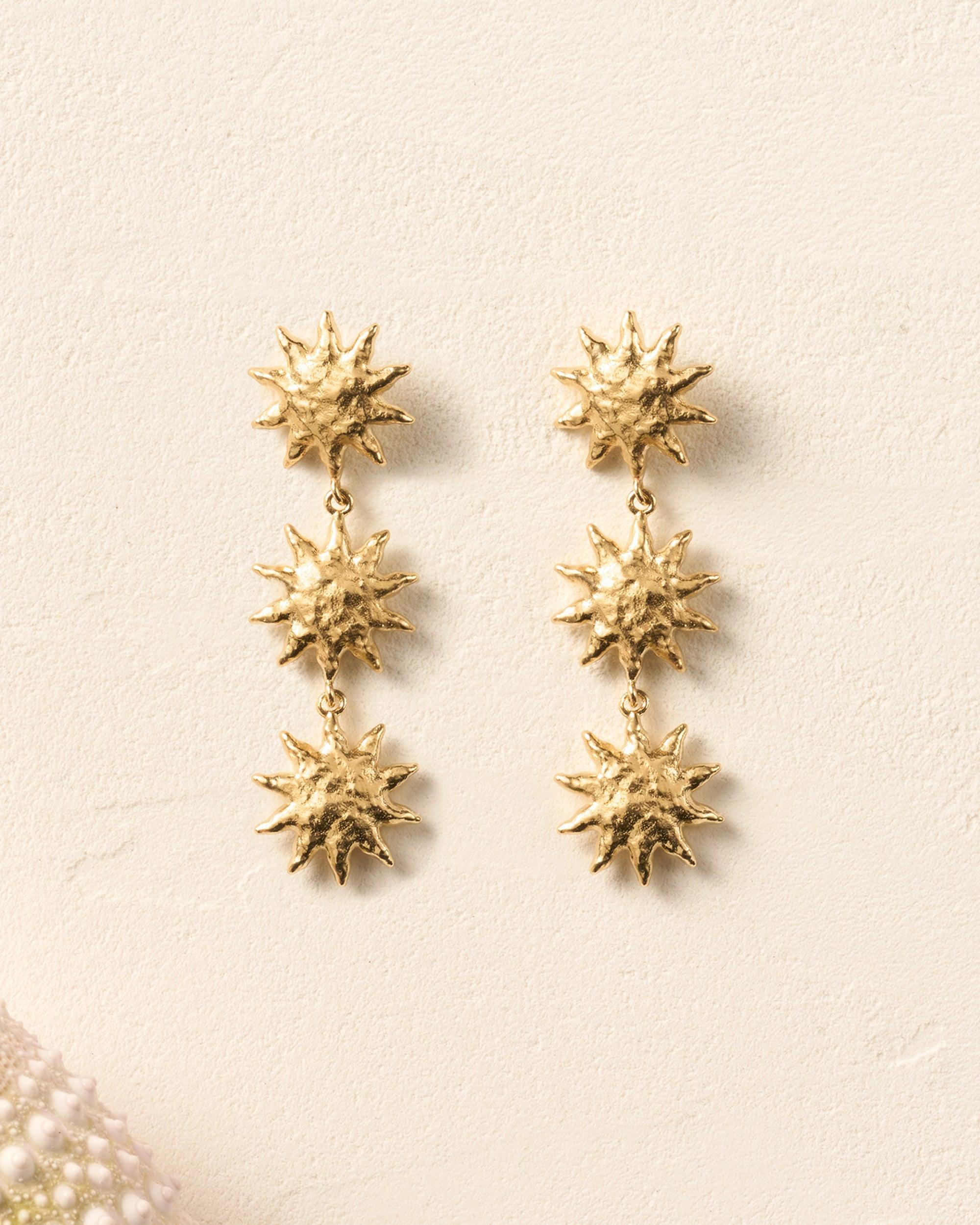 Gold Soléos sun drop earrings with three cascading, hammered, domed suns.