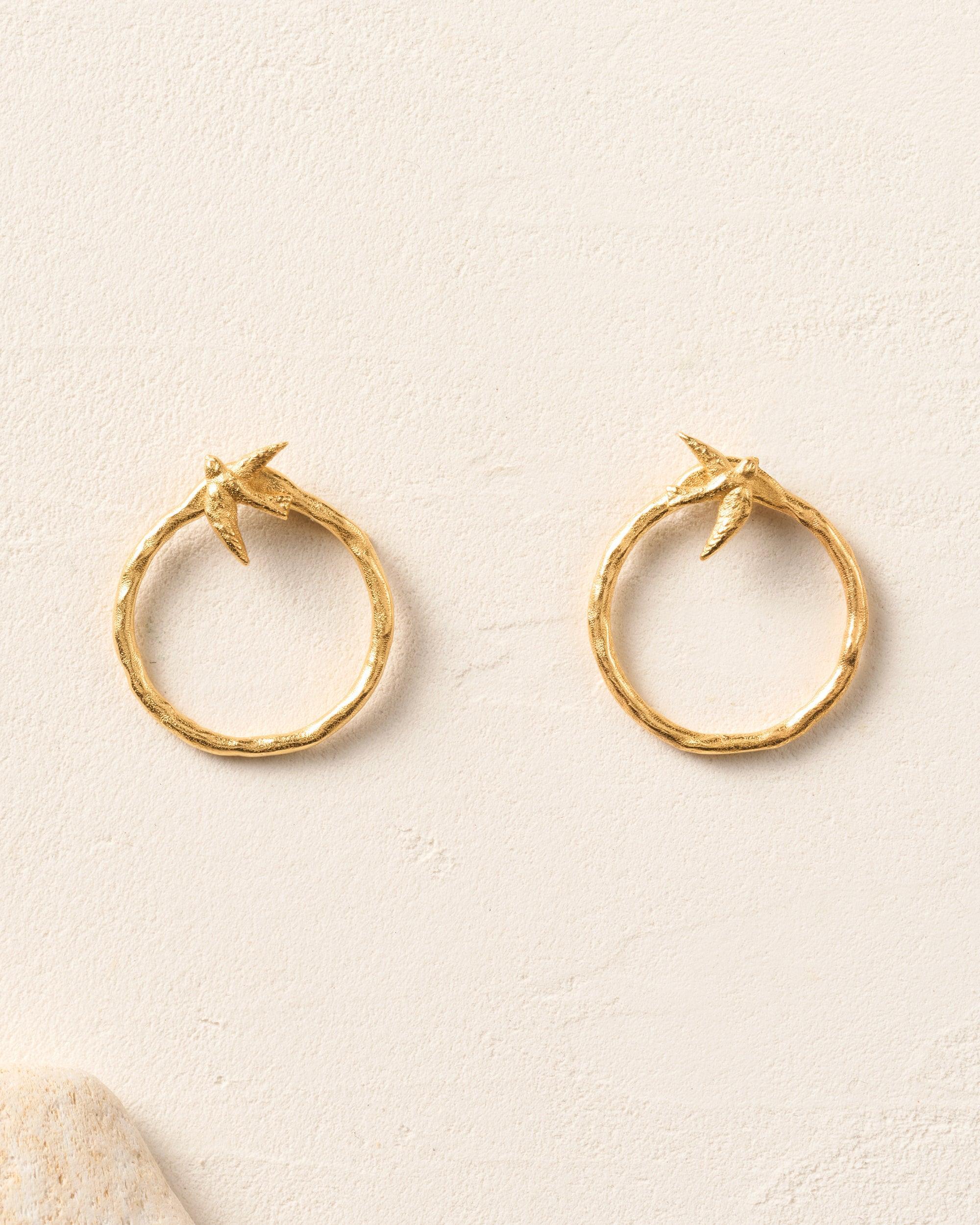 Pair of gold Avila hoop earrings with textured finish and flying bird studs.