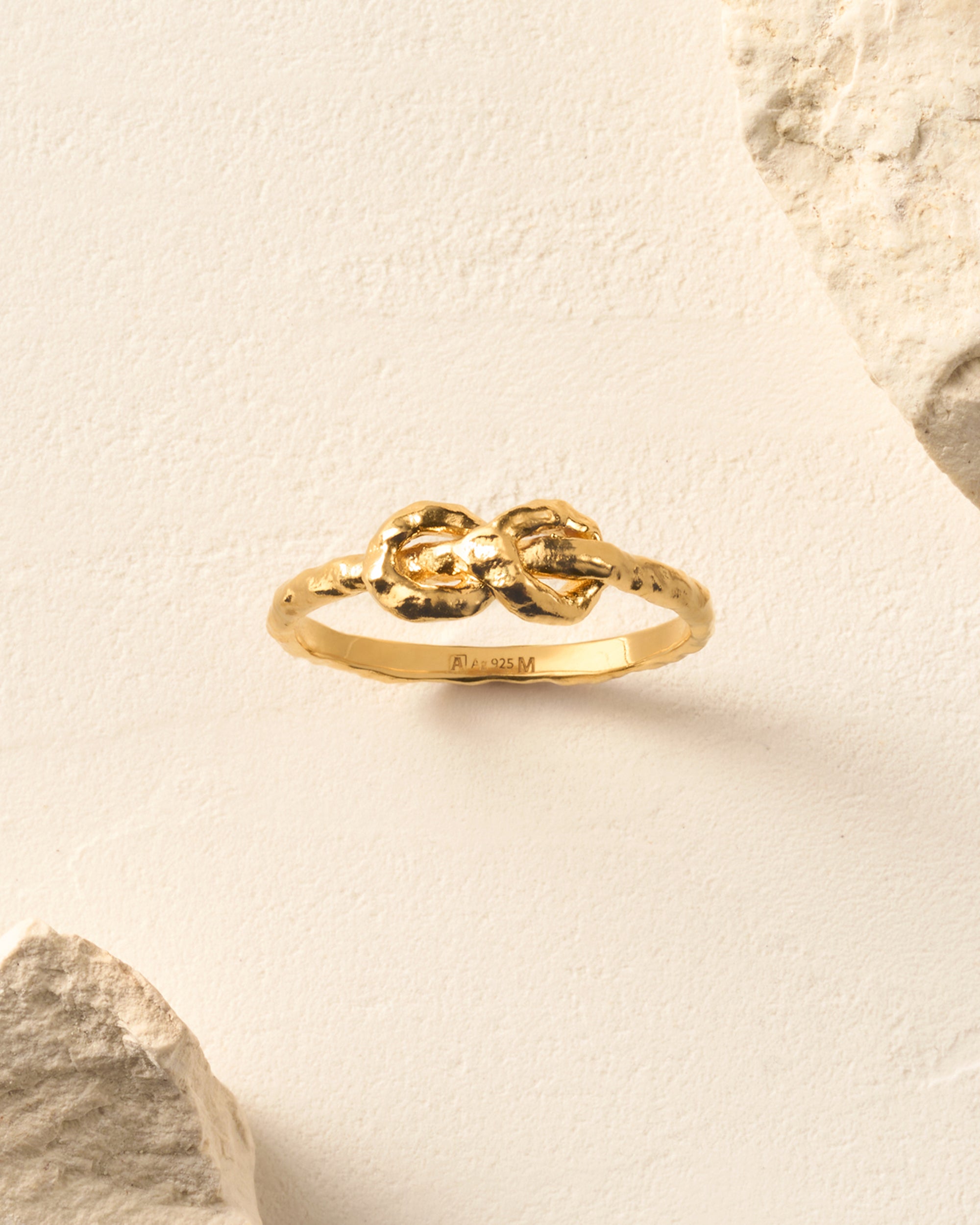 Gold hammered knot ring with two interlocking rope-like strands forming the band.