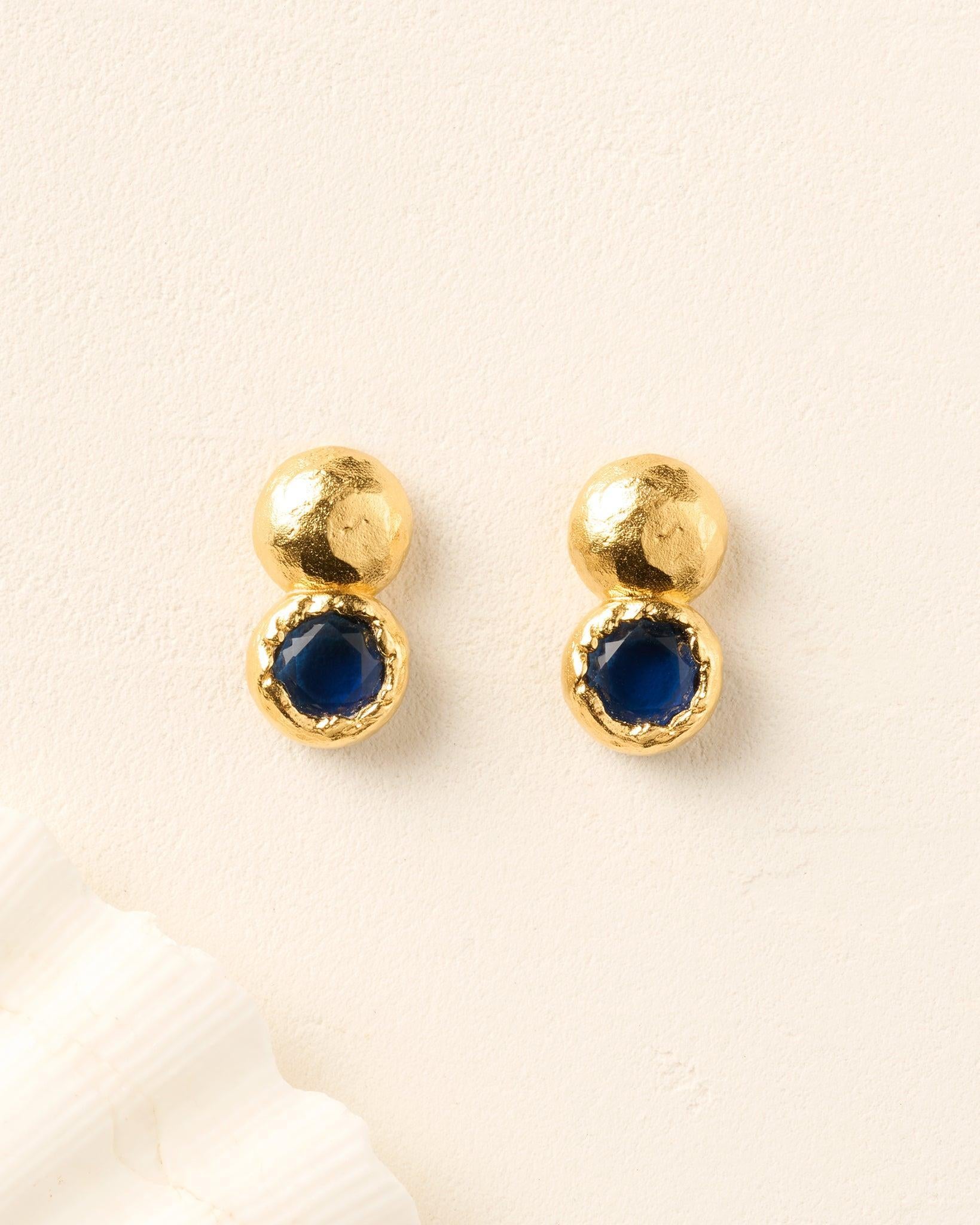 Petra earrings: hammered gold studs with round, deep night blue stones.