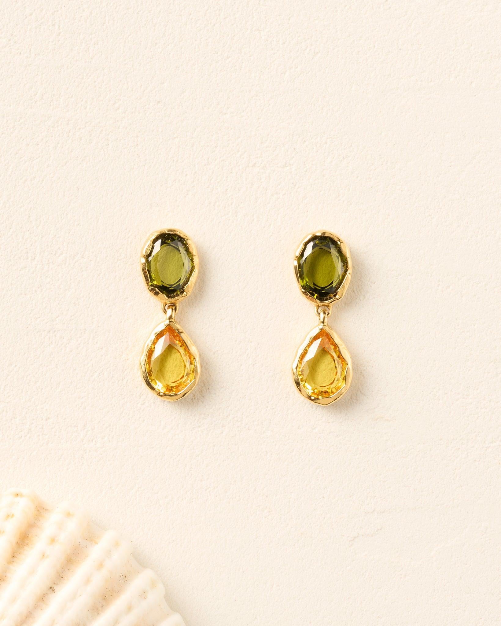 Gold Pedra drop earrings with oval green and faceted yellow pear-shaped stones.