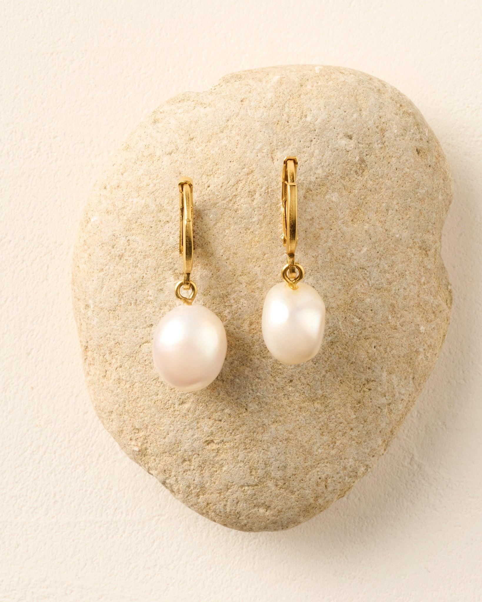 Estée Earrings: Gold hoop earrings with lustrous, irregular white pearl drops on a stone.