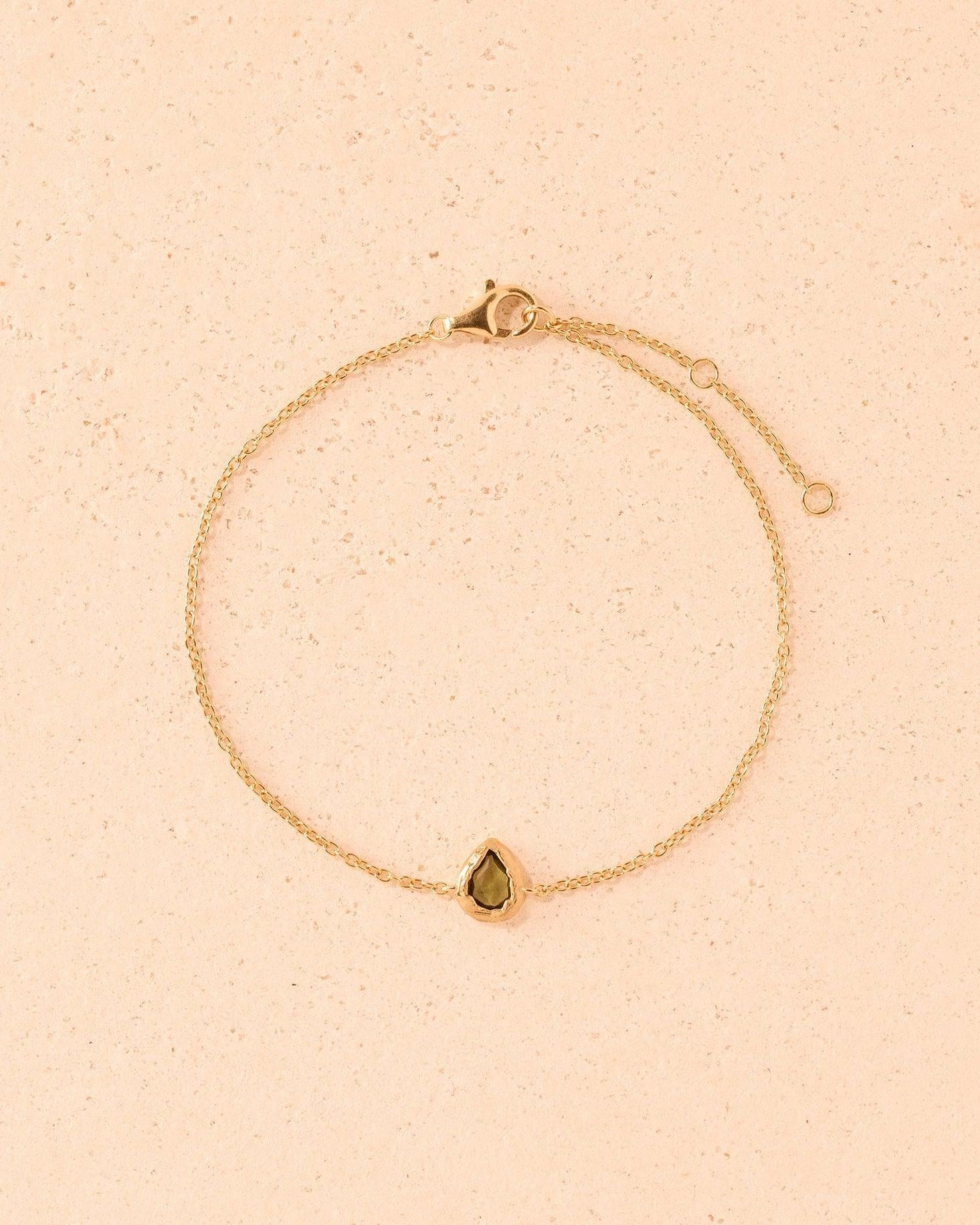 Lysia Bracelet: Fine gold chain with a small, dark-green, teardrop-shaped stone in textured gold.