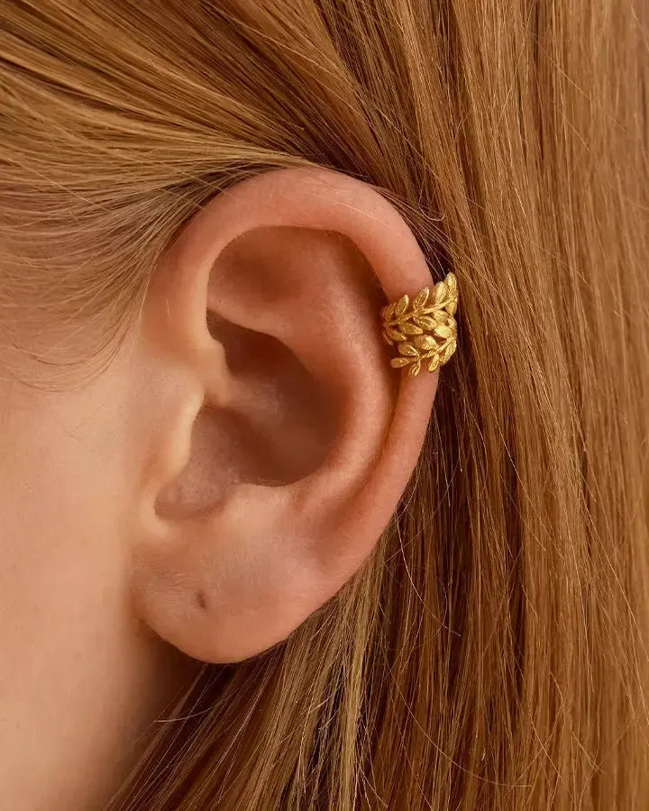 Golden Laurea ear cuff, shaped like laurel leaves, worn on a person's ear.