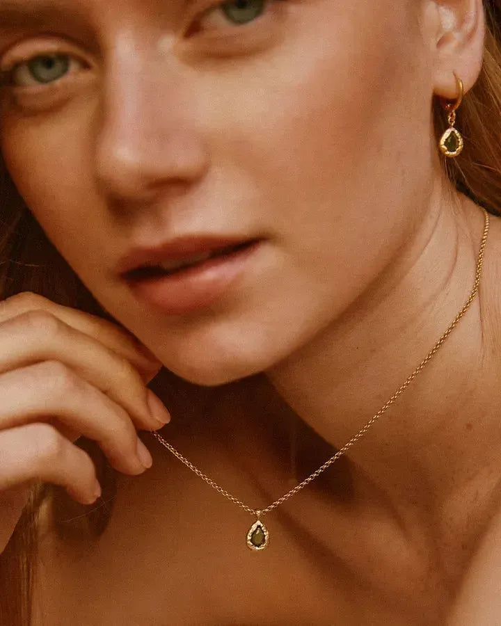 Collier Lysia vert foncé avec pierre en forme de goutte et sertissage doré texturé, sur un mannequin.