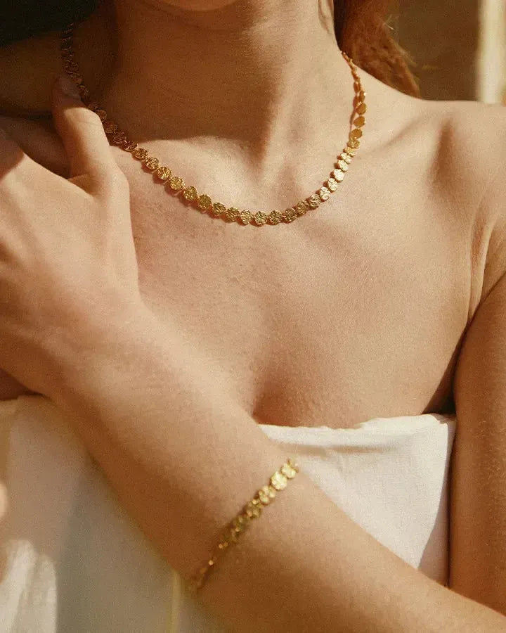 Caius necklace and bracelet with small, hammered gold discs on a woman's neck and wrist.