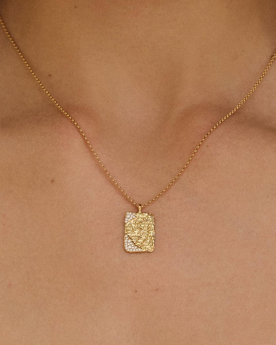 Kálama Halskette: Goldfarbener, gehämmerter, rechteckiger Anhänger mit weißen Steinen an einer zarten Kette.