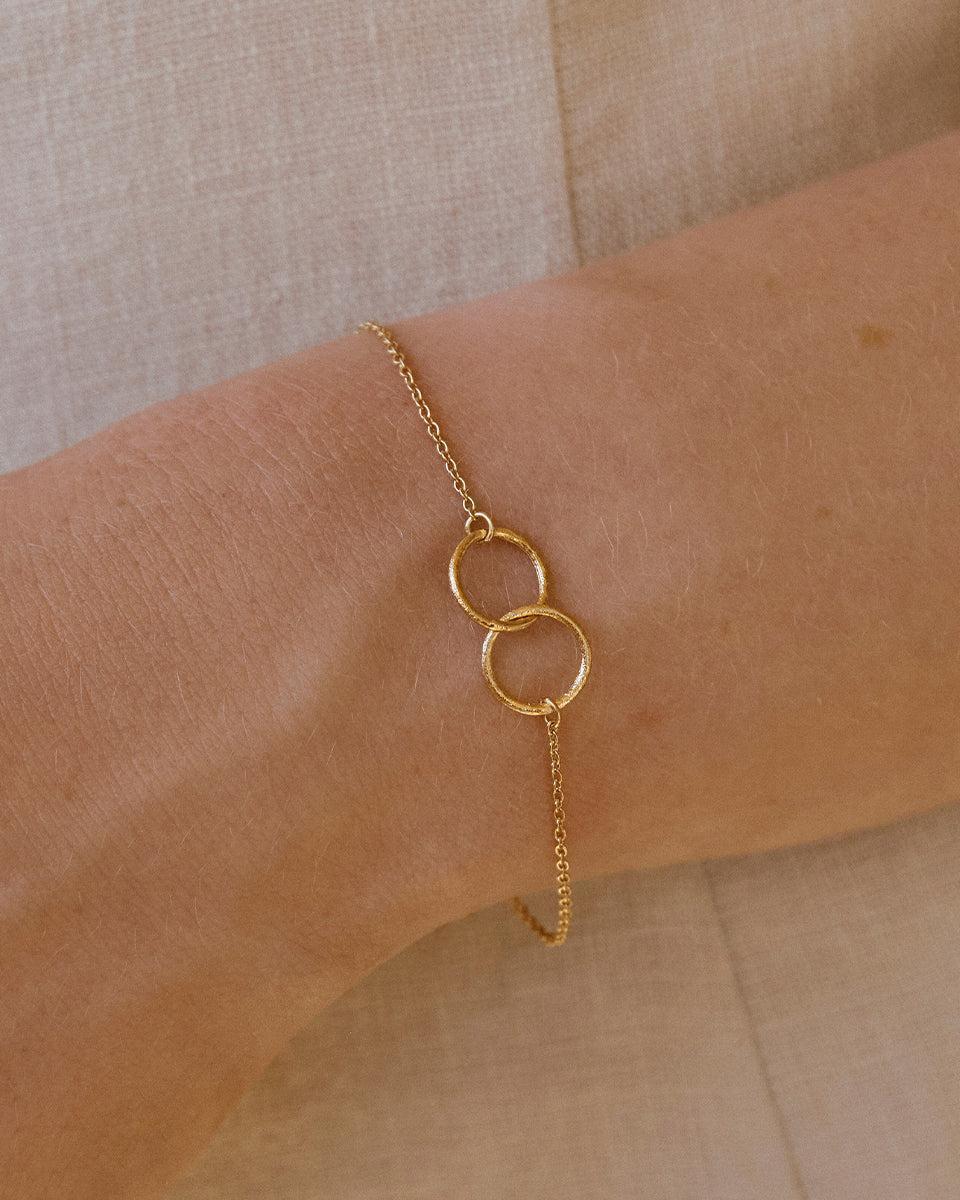 Delicate gold Cirà bracelet with two interlocking circles on a woman's wrist.