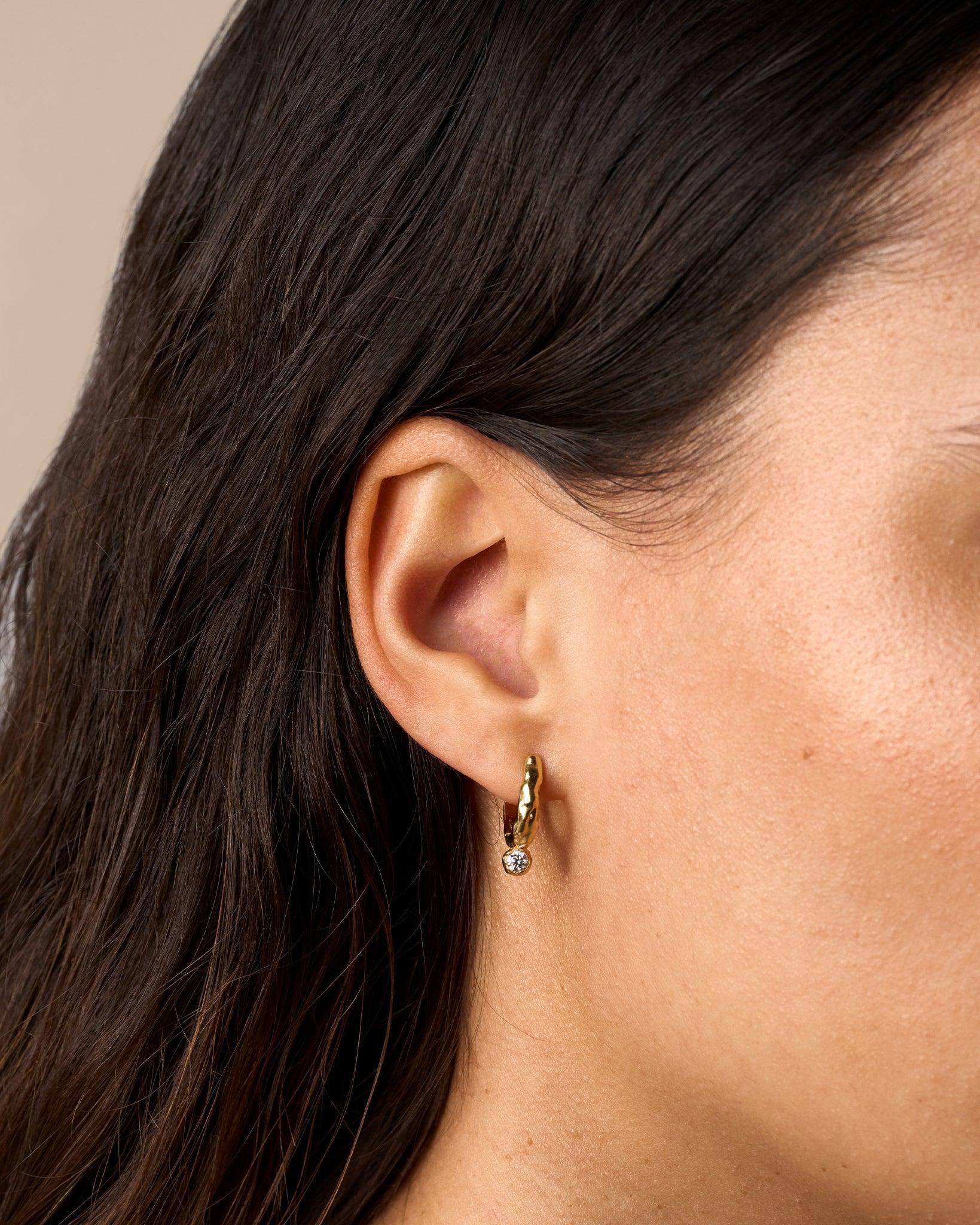 Gold textured hoop earring with a molten surface and a single lab-grown diamond in a bezel setting.