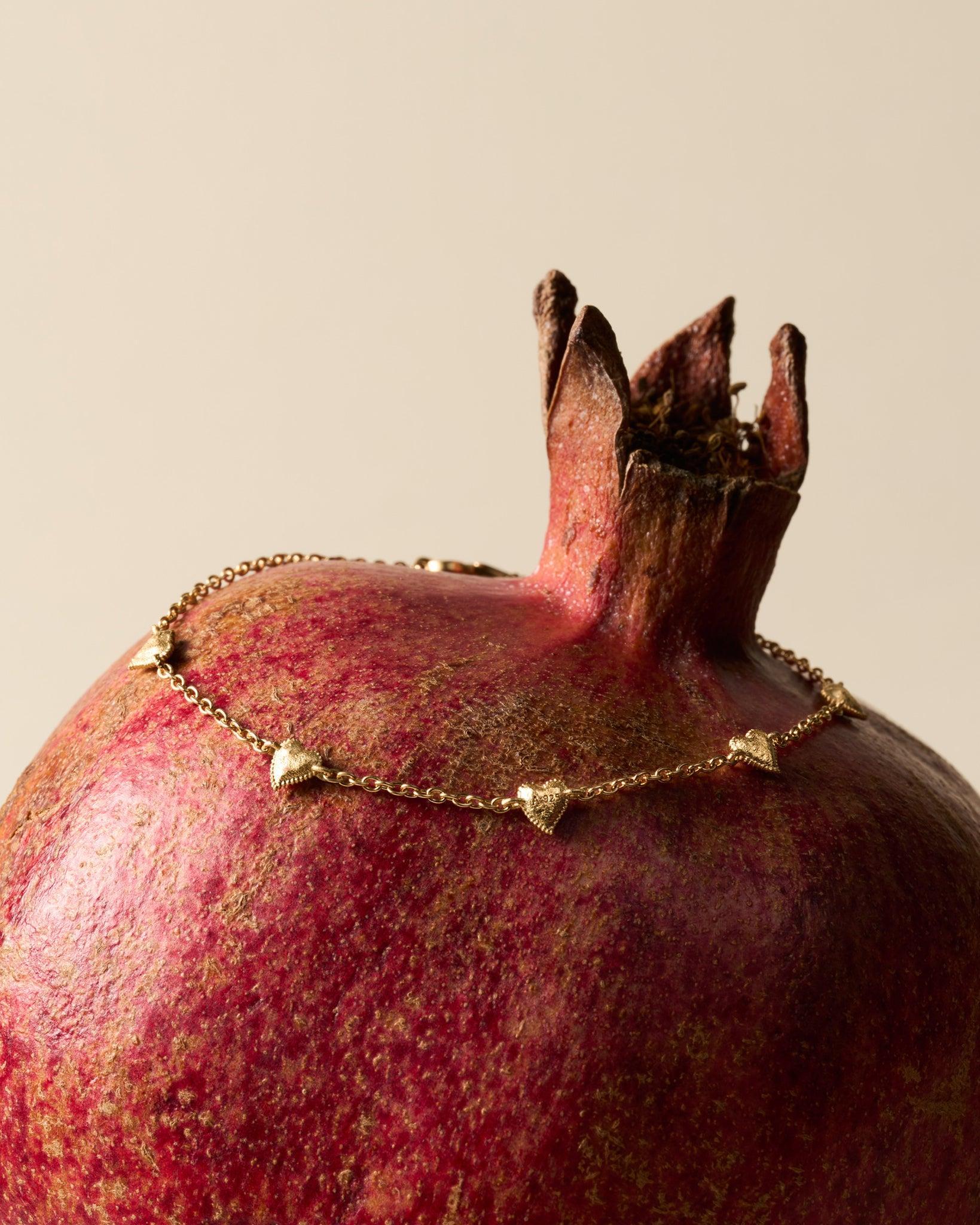 Amori Bracelet: Golden chain with small, hammered, domed heart charms on a pomegranate.