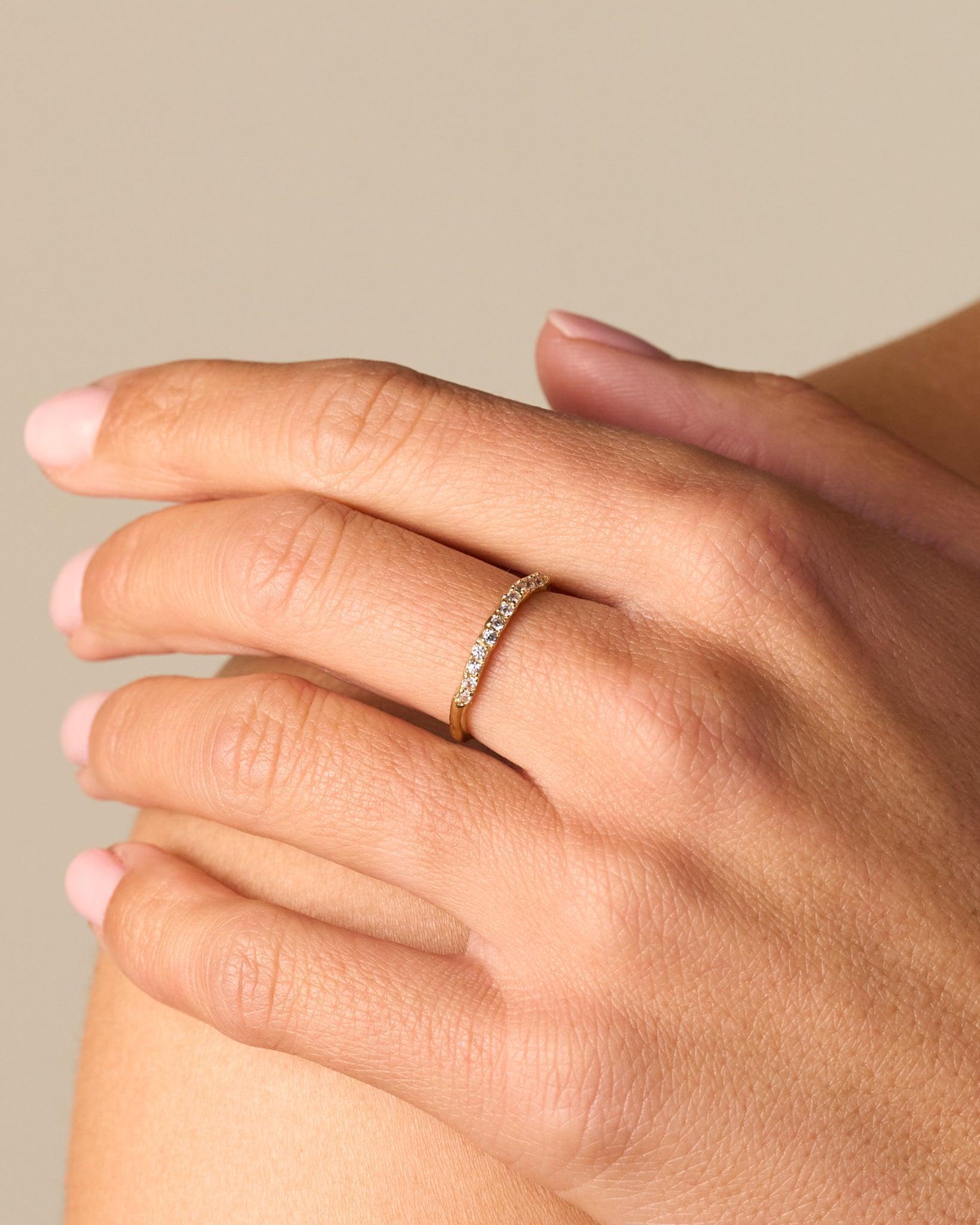 Clara Ring: Gold band with small, irregularly set stones worn on a hand.