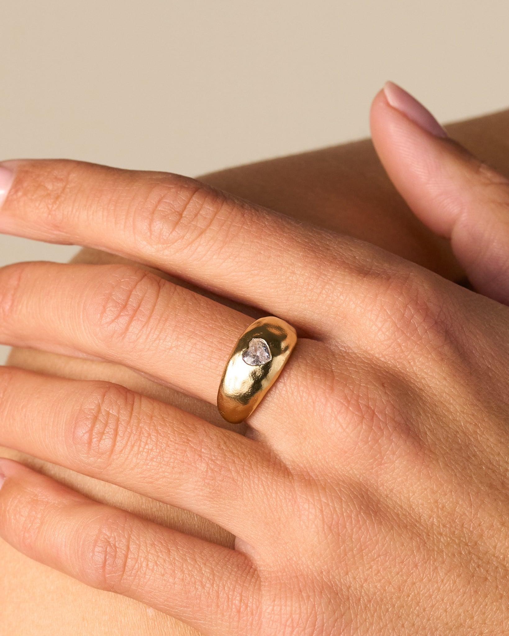 Luzia Ring: Gold domed ring with a white heart-shaped stone on a smooth, slightly hammered surface.