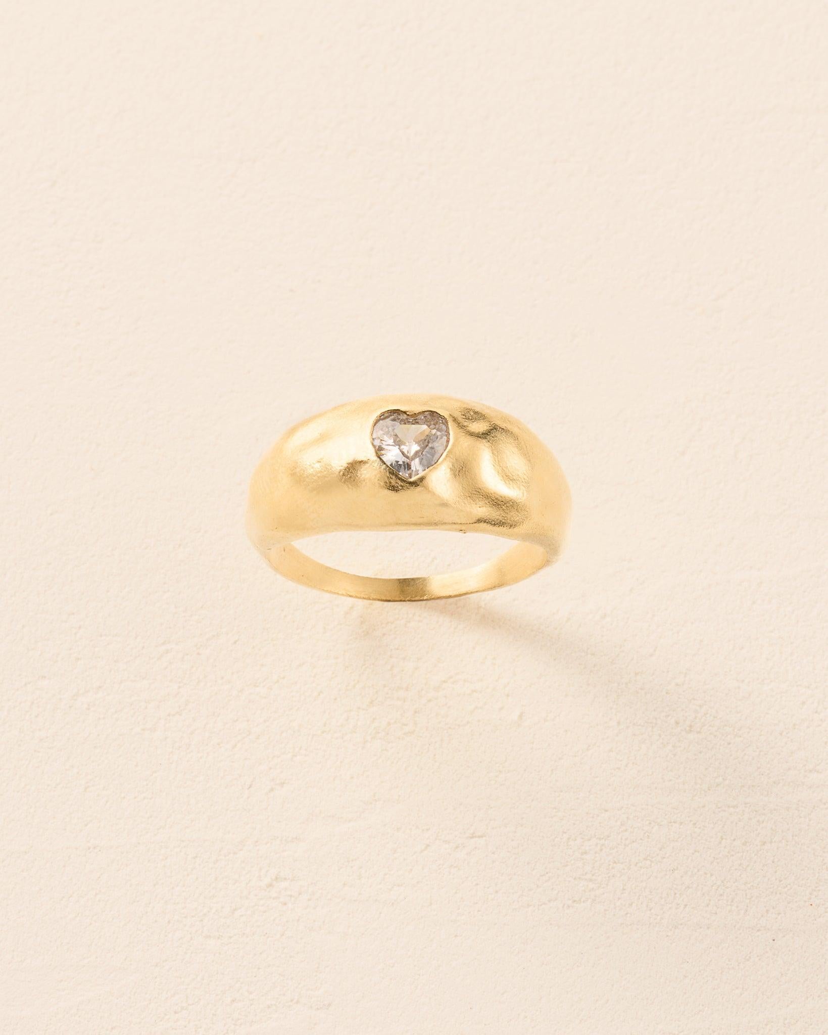Luzia Ring: Gold domed ring with a white heart-shaped stone and hammered surface.