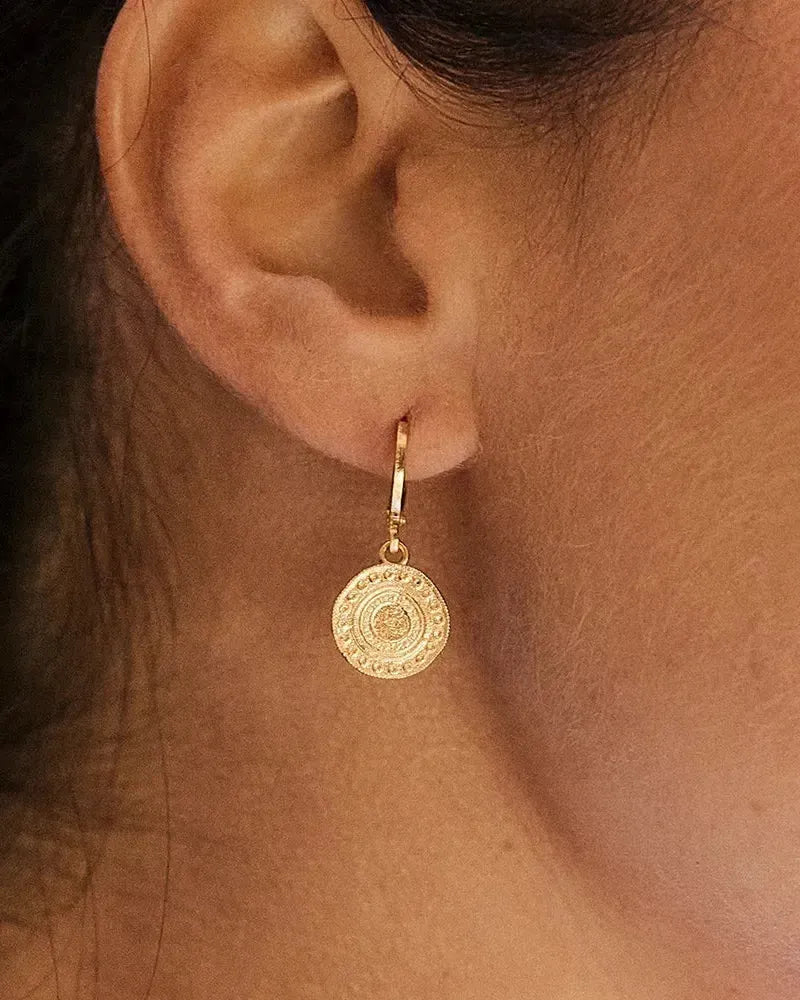 Alba gold-plated earrings with intricate Persian-inspired circular medallions on a woman's ear.