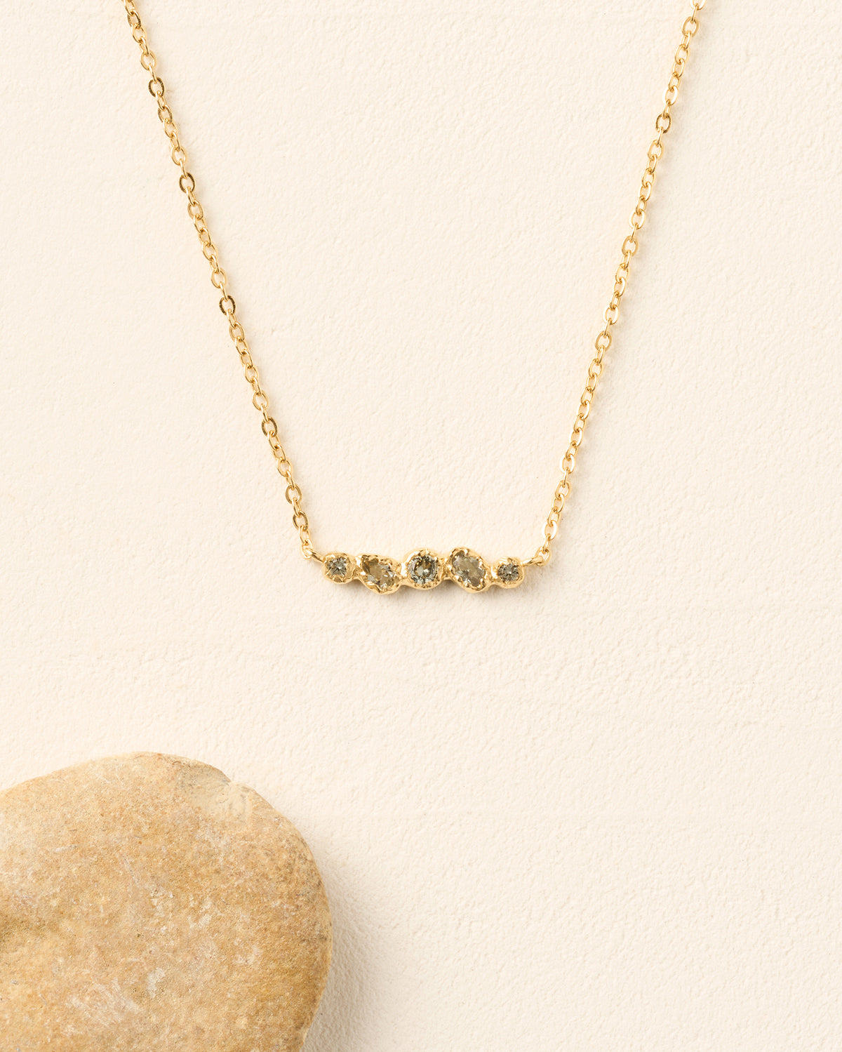 Collar de cadena dorado con un delicado colgante con cinco piedras orgánicas azul verdoso en un engaste texturizado.
