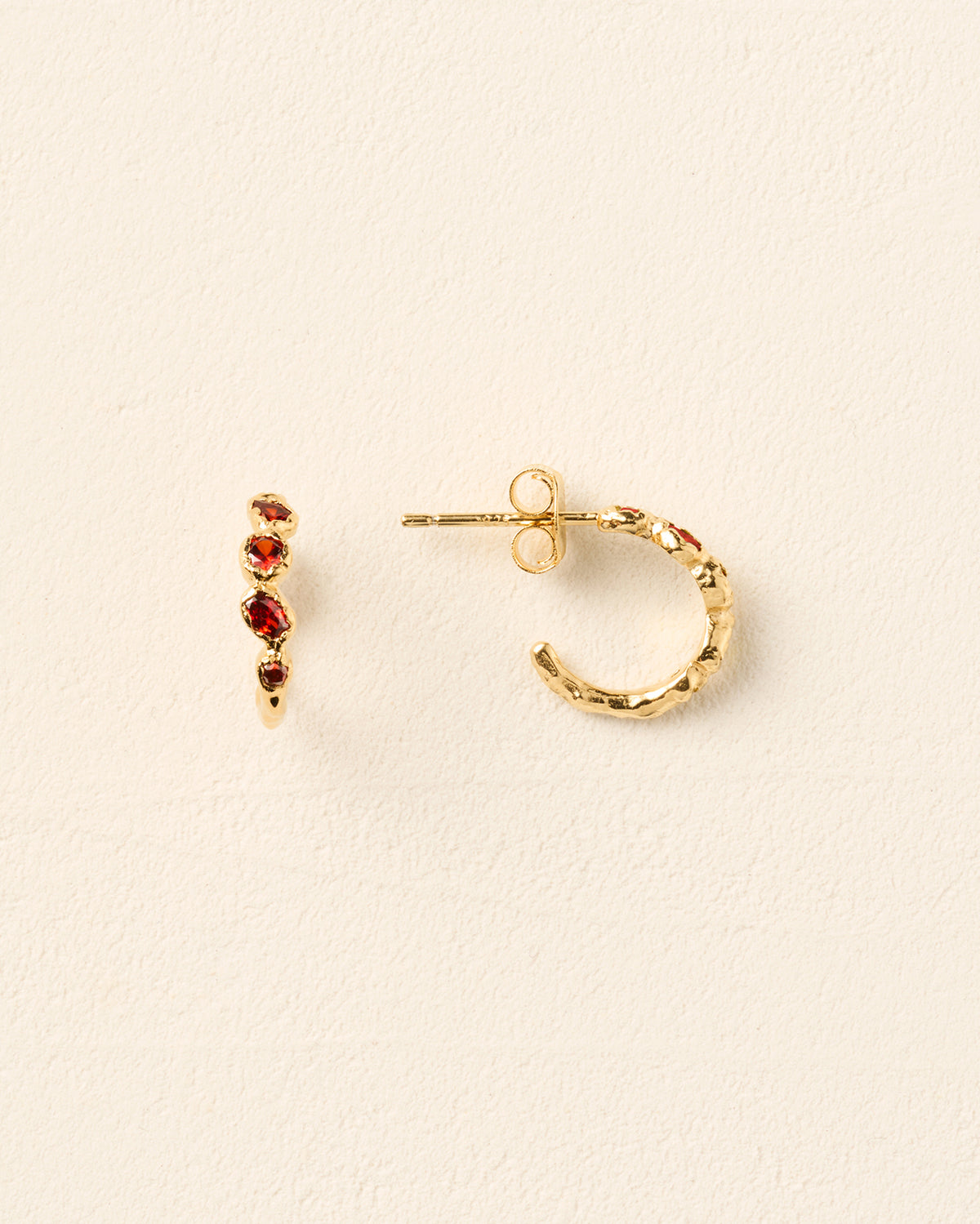Gold hoop earrings with a textured finish, each set with five deep red stones in a delicate, antique-inspired design.