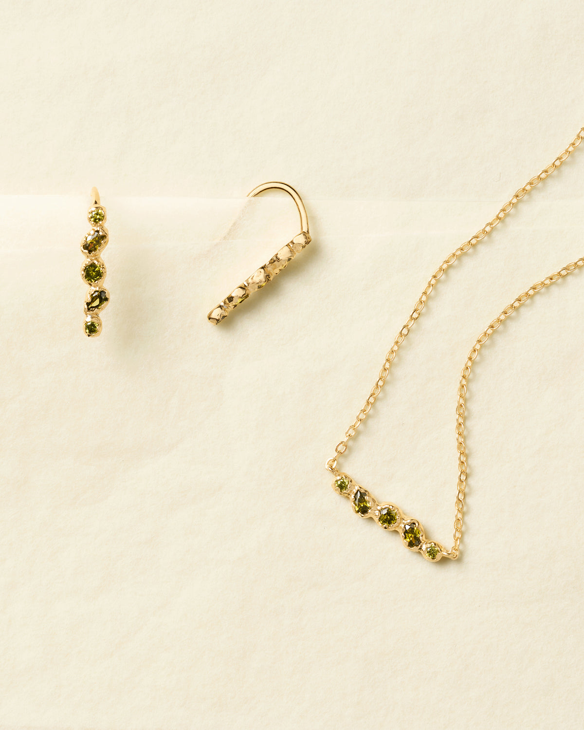 Gold drop earrings and matching necklace featuring five organic, deep green stones set in textured metal.
