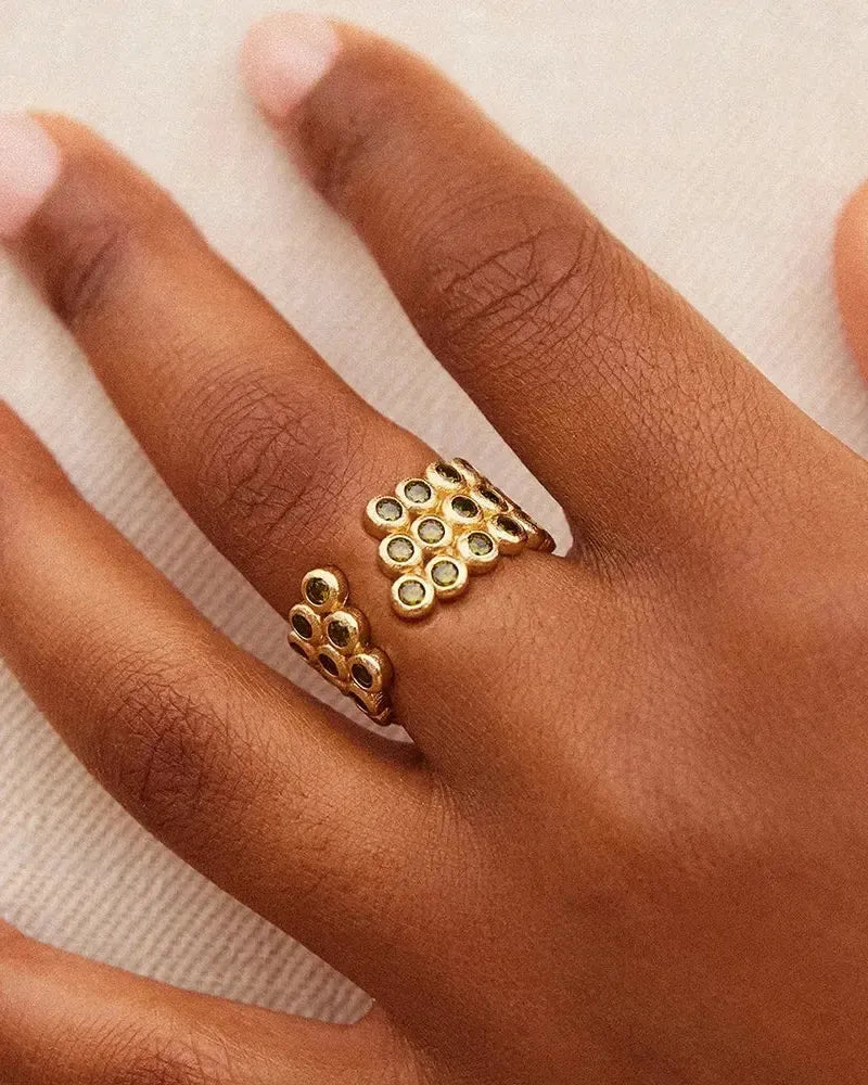 Amélia Trio Dark Green Ring: Gold ring with three stacked bands, featuring multiple dark green embedded stones in a geometric design.