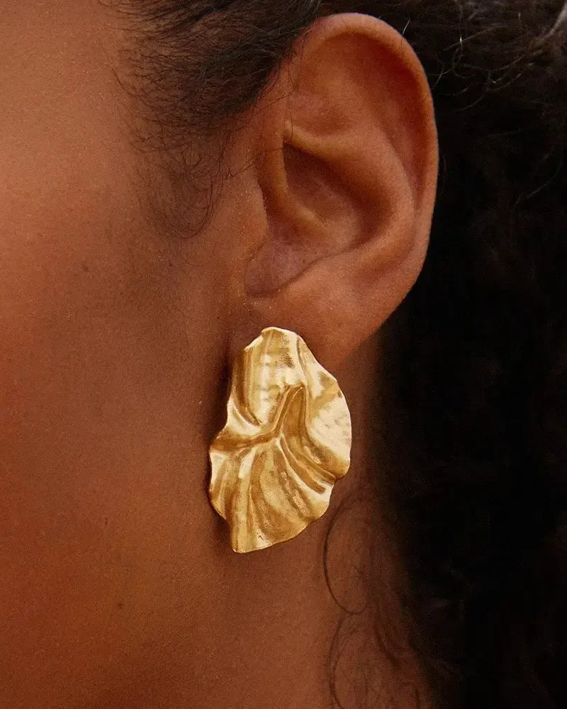 Gold Batla earrings with a soft petal, fabric-like texture, worn on an ear.