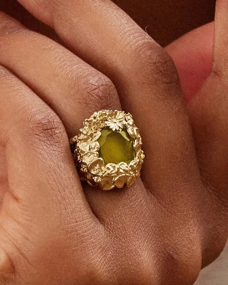 Hespé chunky gold ring with a striking green stone cradled in a bed of floral details.