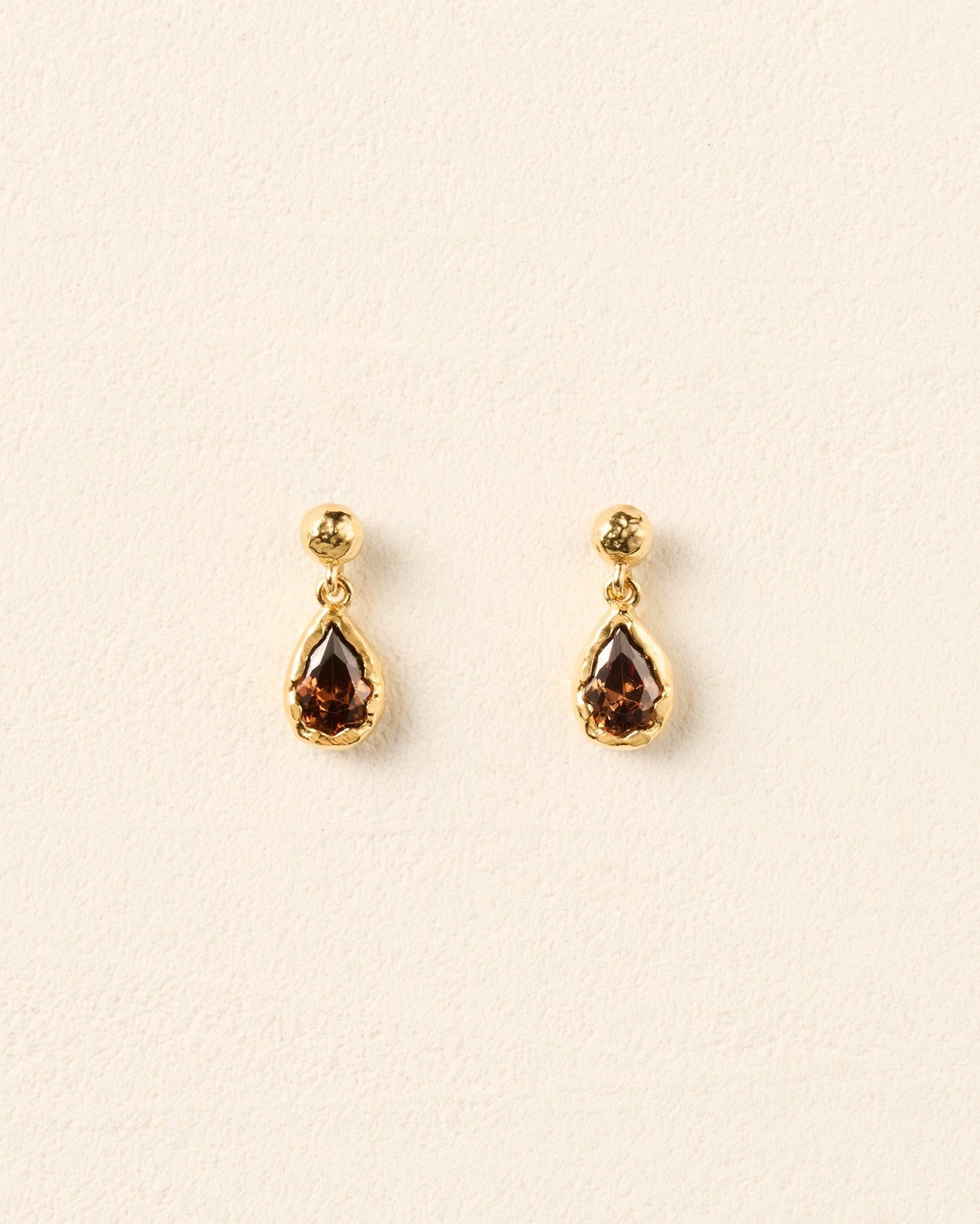 Lyséa drop earrings featuring pear-shaped brown stones in textured gold settings suspended from hammered gold studs.