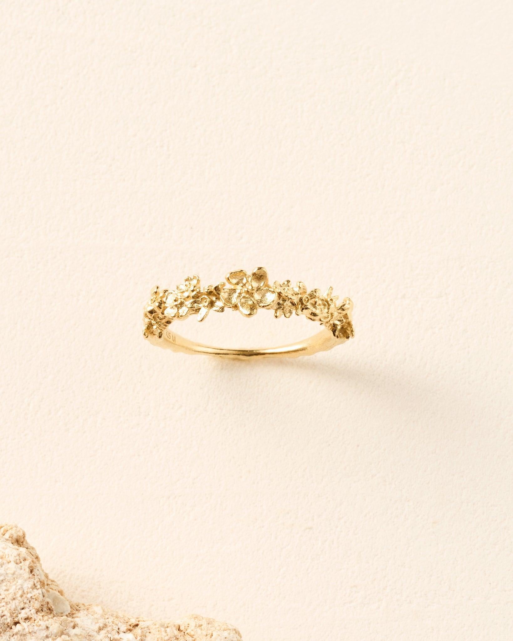 Gold Kèpia ring featuring a textured, sculpted floral garland design with irregular petals on a delicate band.