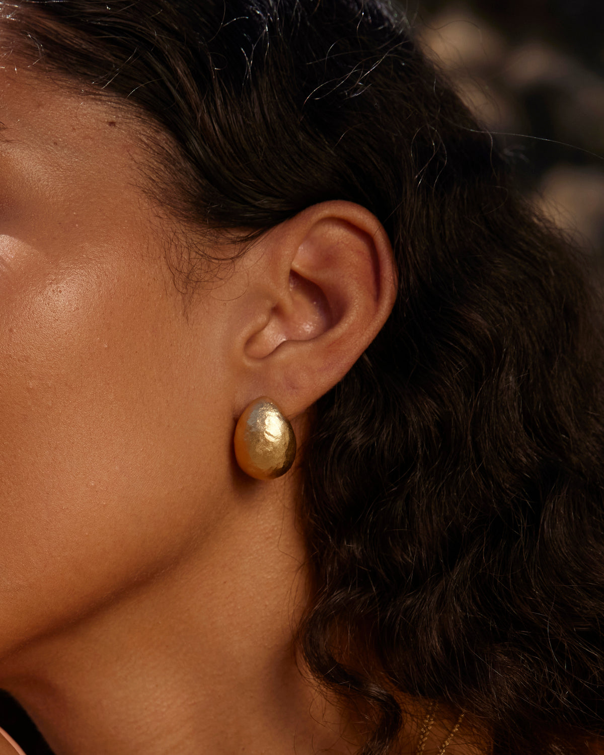 Sculptural gold Figuera earrings with a domed, fig-inspired shape worn on an earlobe.