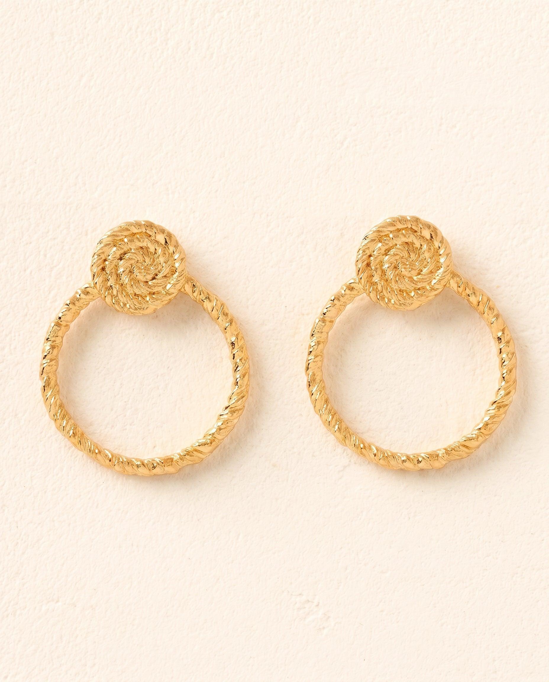 Gold Zeti hoop earrings featuring a twisted rope texture and a circular braided spiral accent at the top.