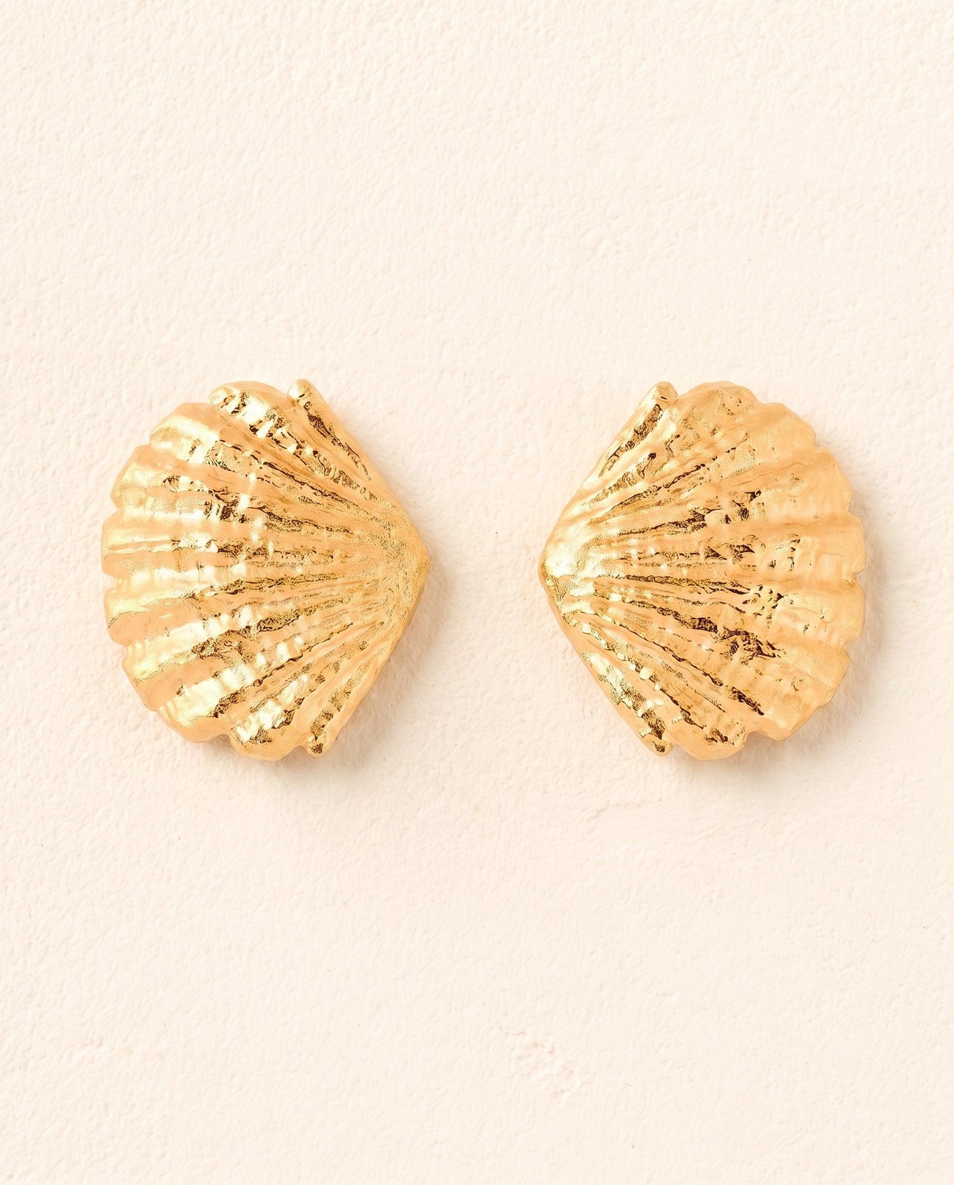 Pair of large gold sculptural seashell earrings with wavy, ridged, fan-like design and scalloped edges.