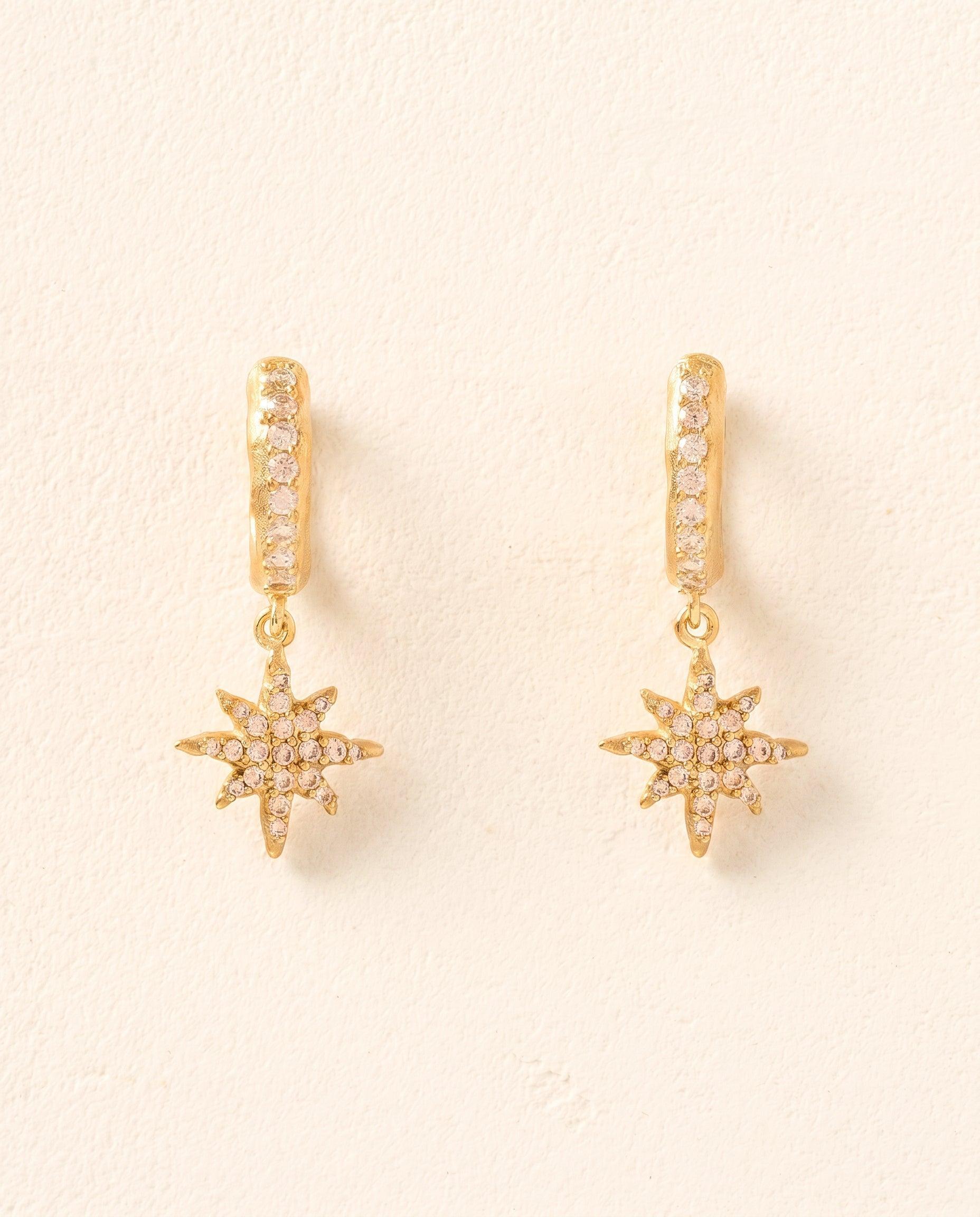 Gold hoop earrings with pavé-set white stones and dangling star pendants.
