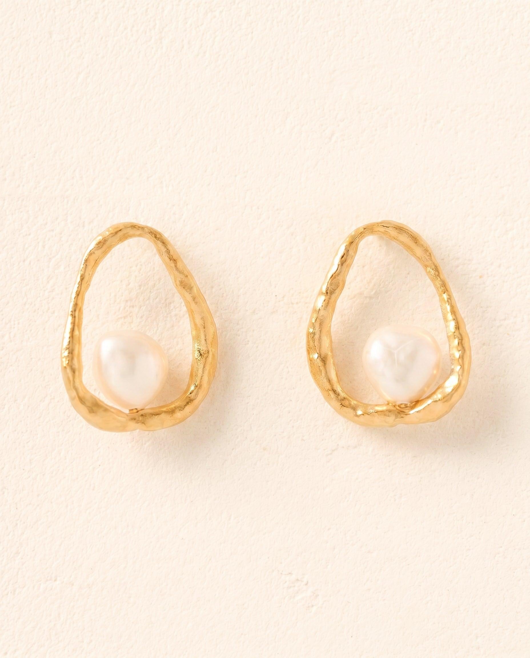 Ostuni earrings: gold-toned, hammered metal hoops with floating white mother-of-pearl pendants.