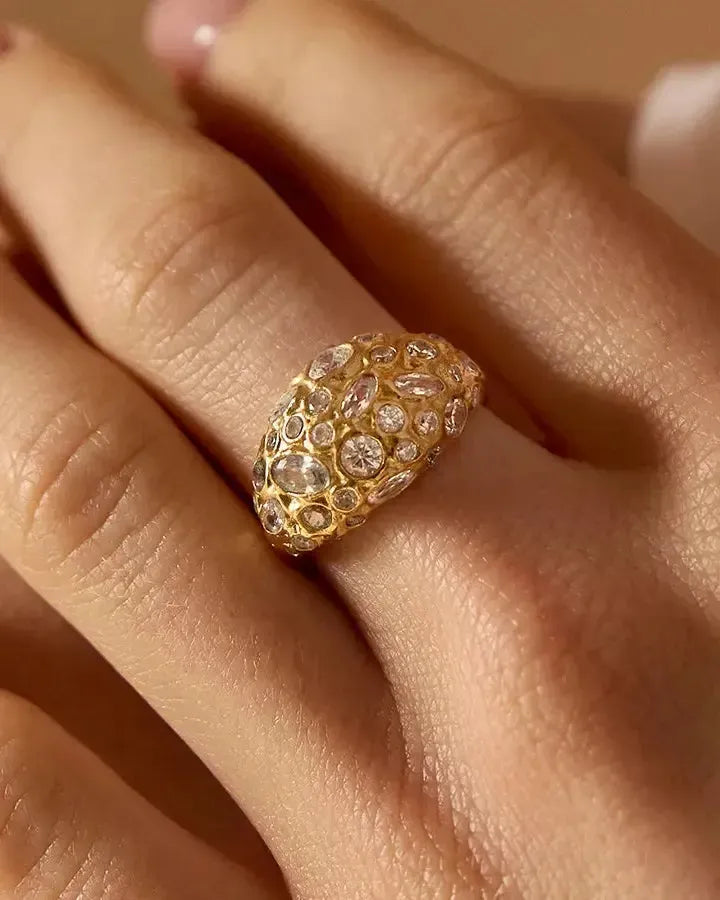 Gala gold dome ring with irregularly pavé-set white stones of various sizes on a finger.