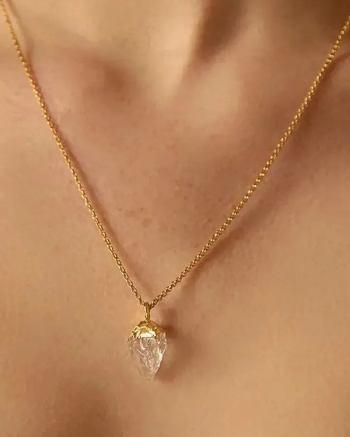Collar Dioné: colgante de cuarzo transparente con engaste dorado irregular, en una fina cadena dorada.
