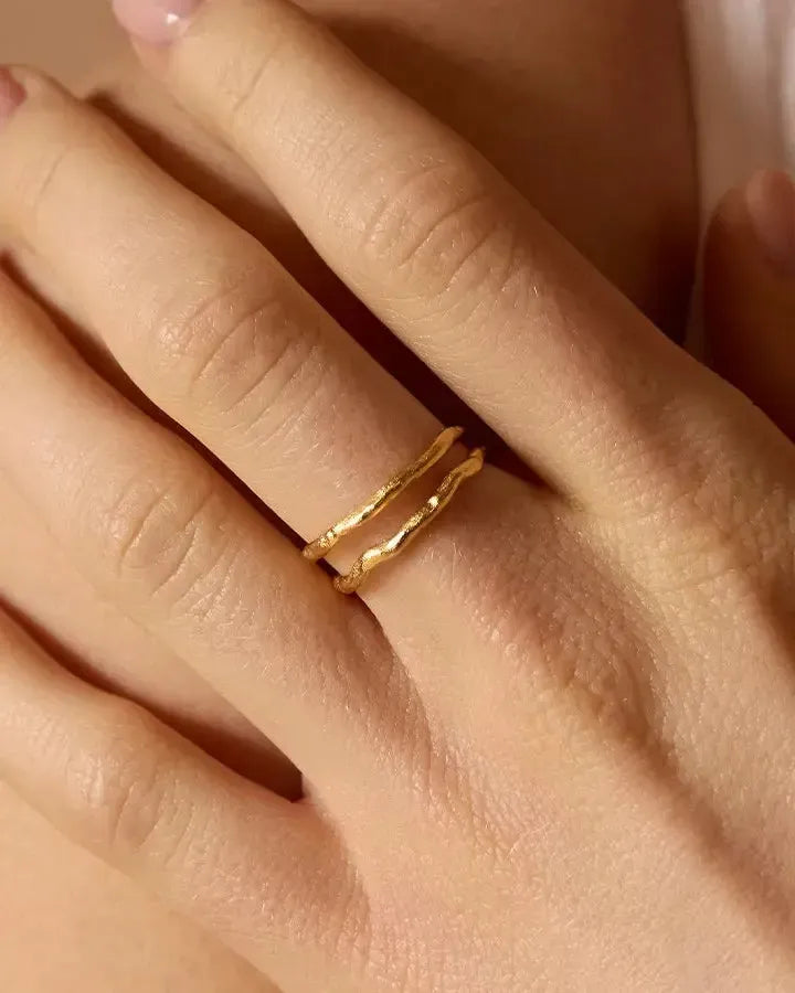 Gold Léna twin ring with two stacked, irregular, textured bands on a finger.