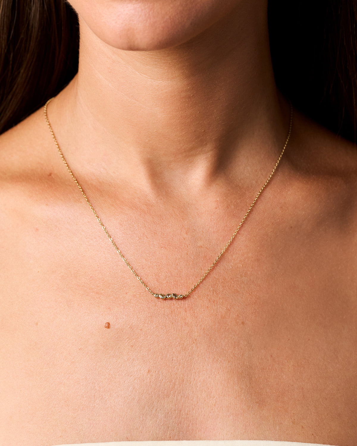 Collar de cadena dorado con cinco pequeñas piedras orgánicas azul verdoso engastadas en un delicado colgante irregular.