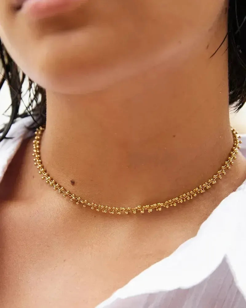 Achille Choker: Gold beaded chain necklace on a woman's neck, elegant and luminous.