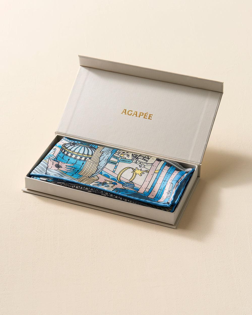 Atlantis Silk Scarf by Agapée in a grey box, featuring blue, pink, and gold Mediterranean-inspired art.