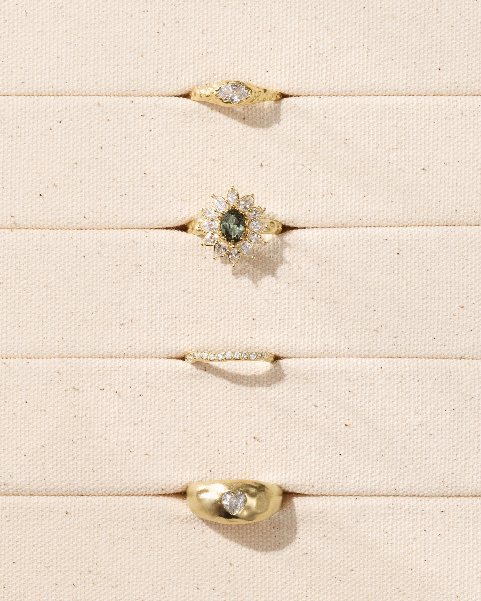 Calia cocktail ring: blue-green center stone, clear pear-cut stones, gold hammered band.