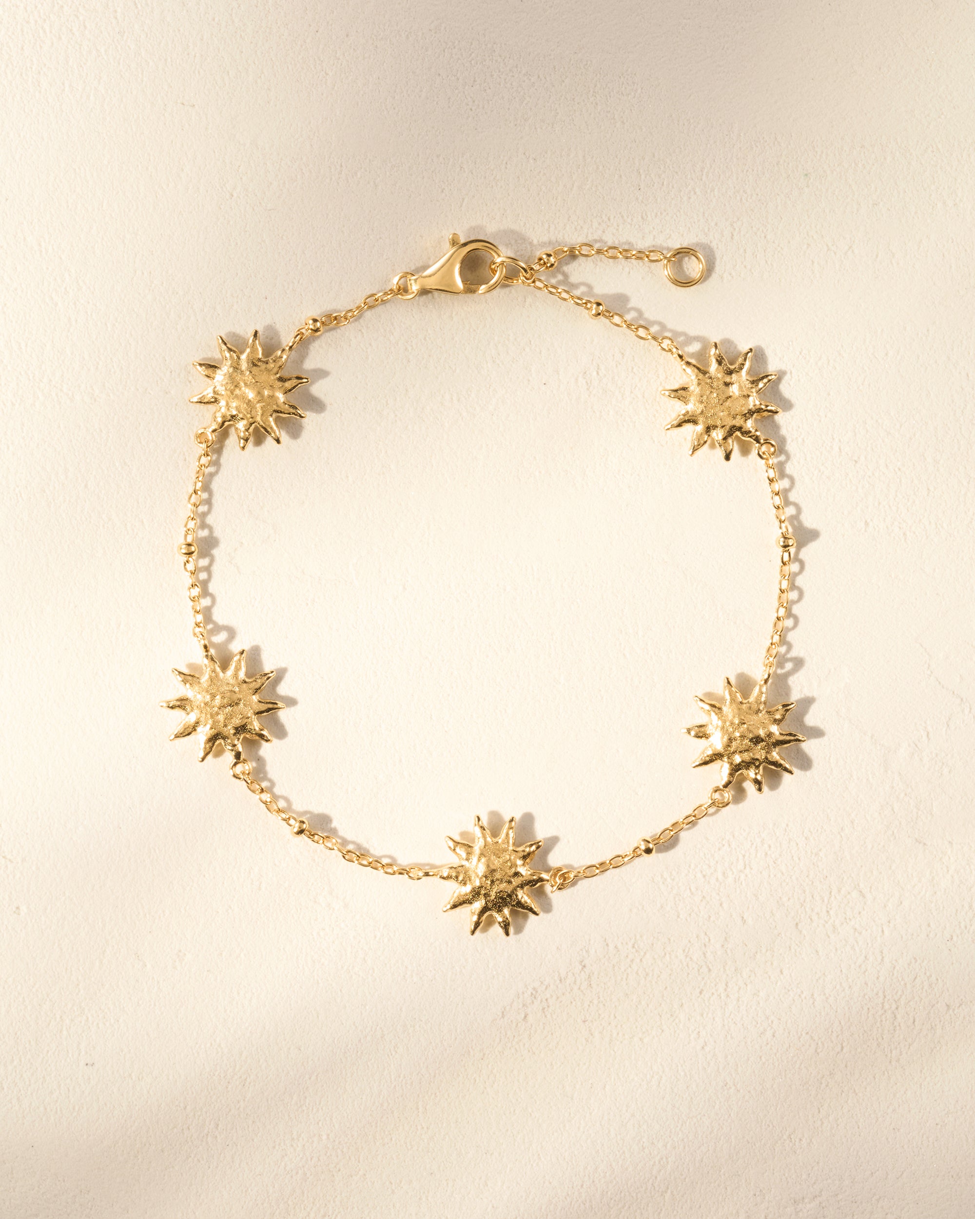 Gold Soléos Bracelet with five sculpted, hammered sun charms on a fine chain.