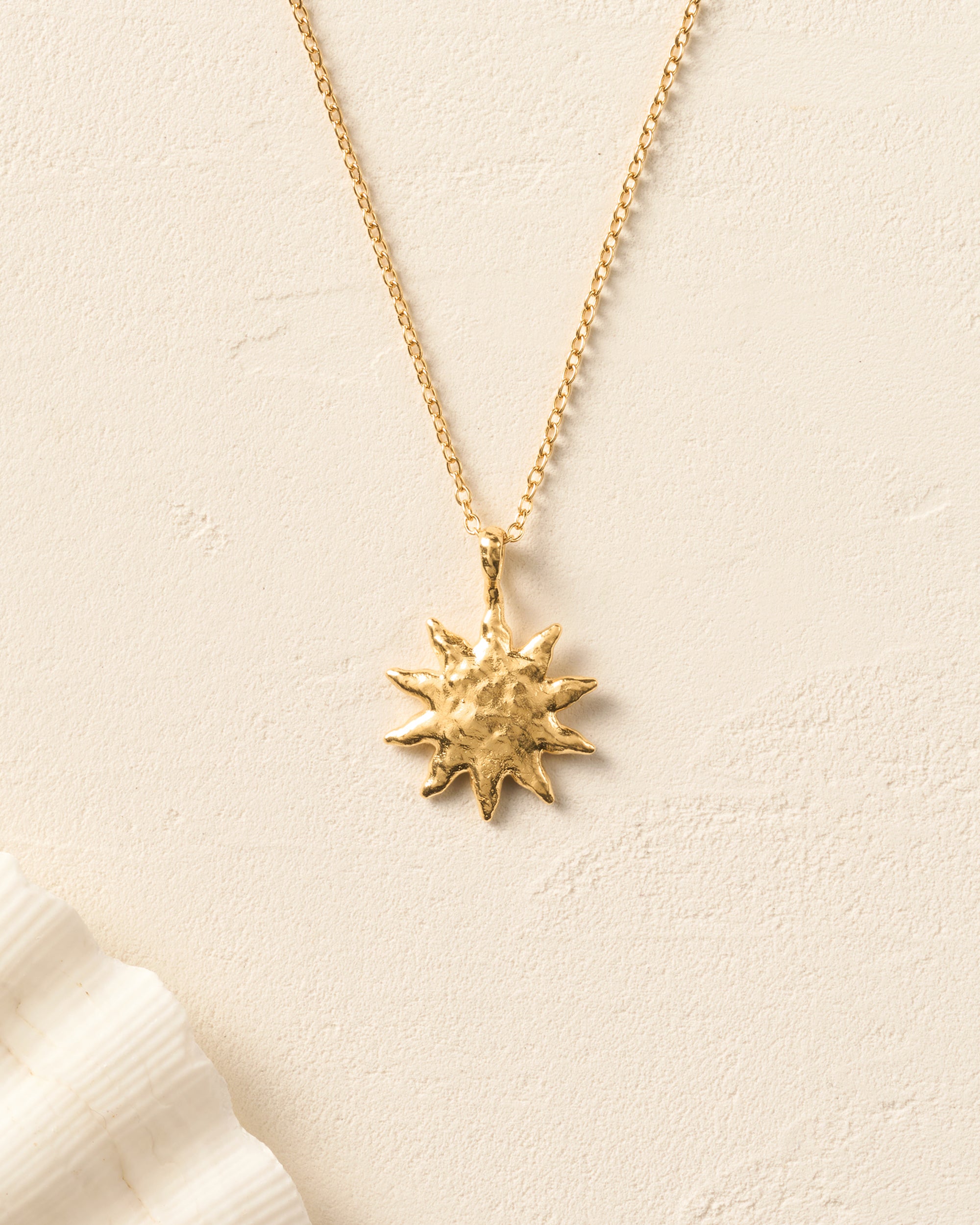 Gold Solé sun pendant necklace with a hammered, domed surface on a fine chain.