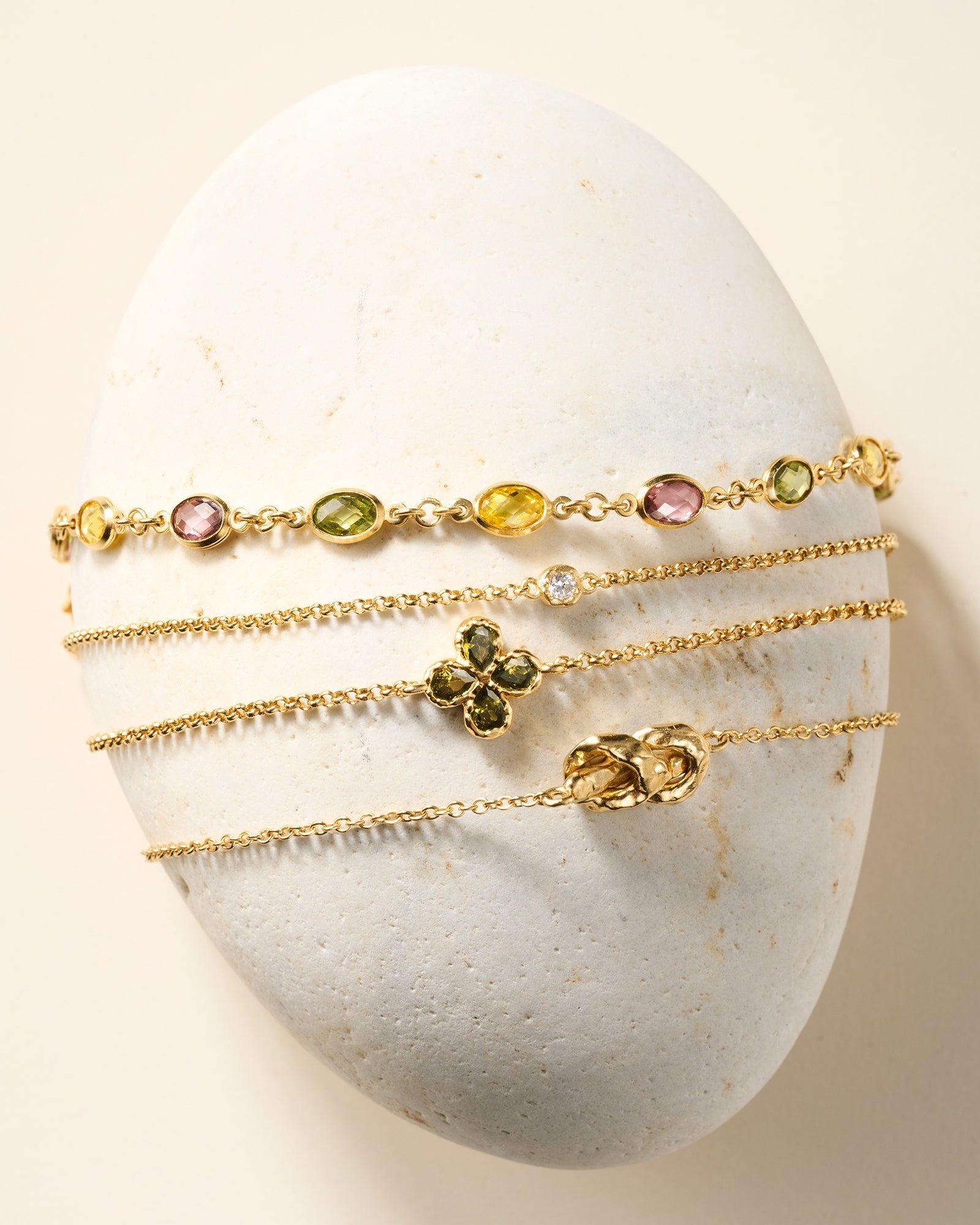 Fausta bracelet: gold chain with a four-leaf clover charm, each leaf a deep green pear-cut stone.