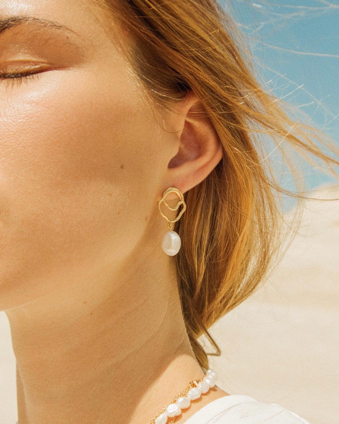 Célaphine gold earrings with an organic top and a dangling baroque pearl.