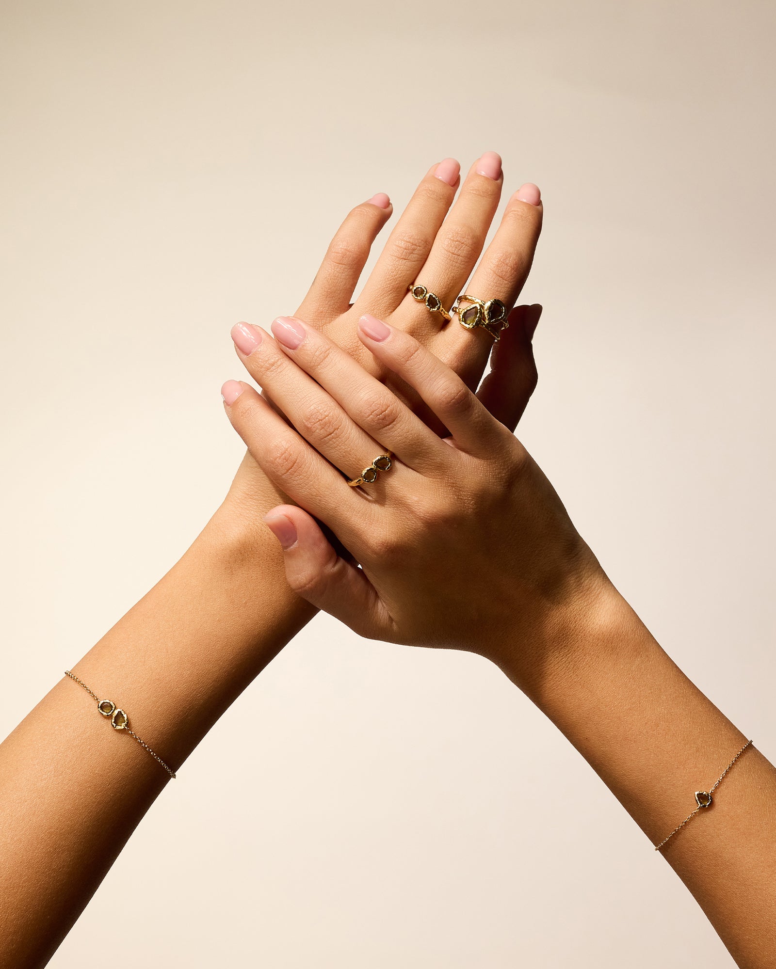 Lysia Bracelet with dark-green stone in textured gold, worn on a wrist with matching rings.