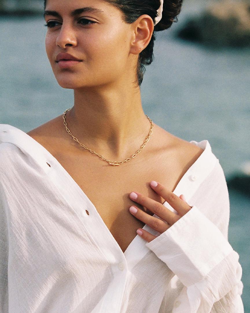 Woman wearing a gold Horace Mini Choker with intertwined links and a sleek toggle clasp.