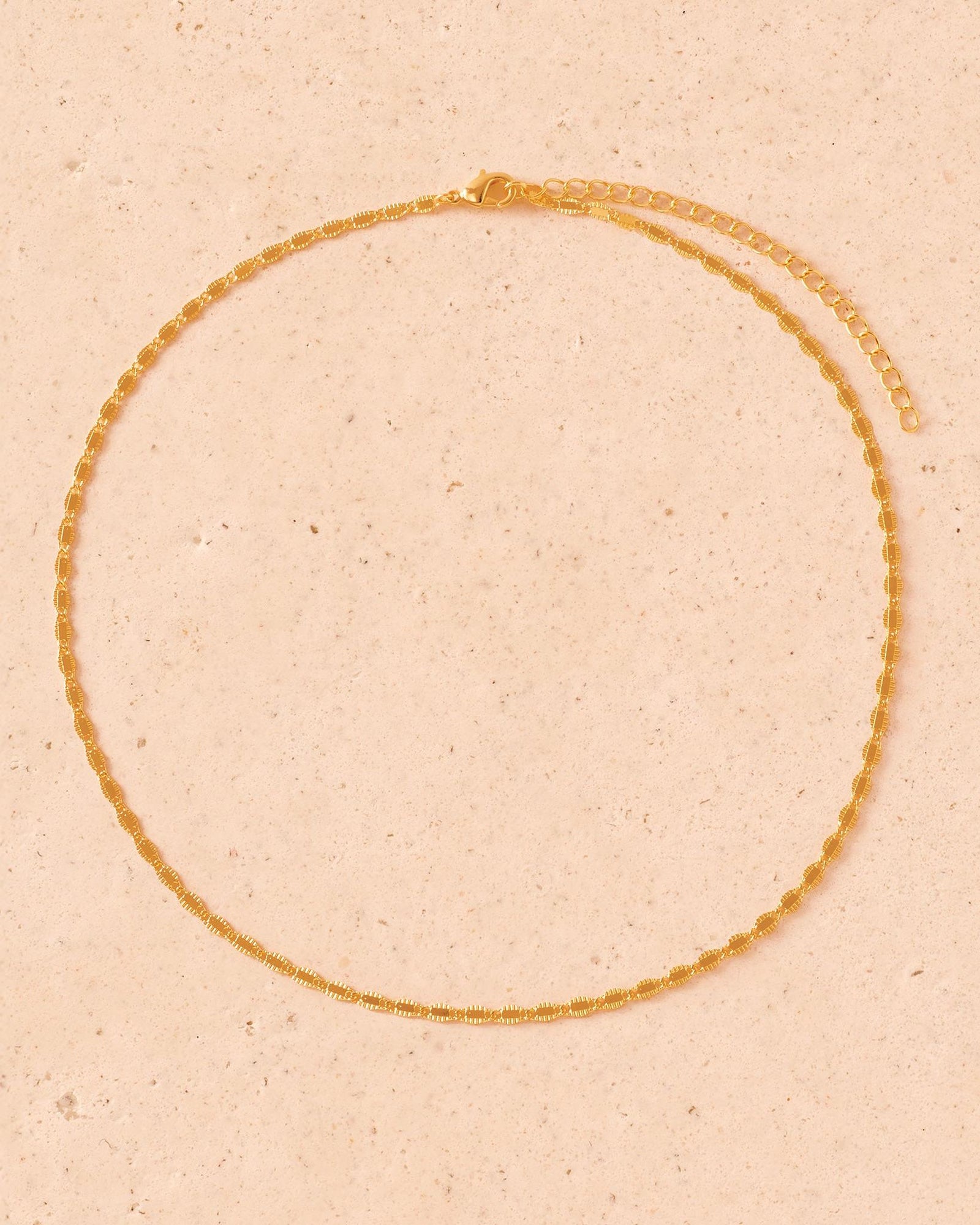 Gold Isidore choker with unique helix link design, adjustable clasp, on a light textured background.