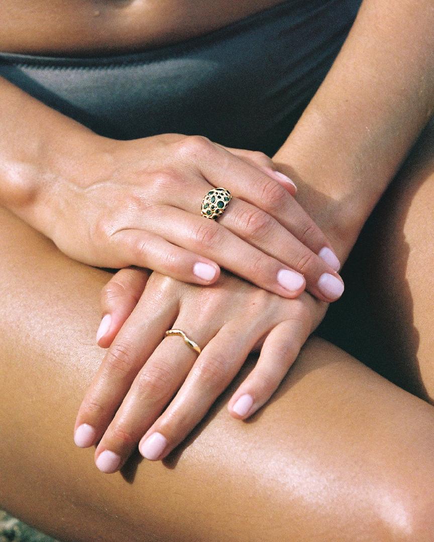 Gold Satis Ring, thin and twisted, worn on a hand with light pink nail polish.